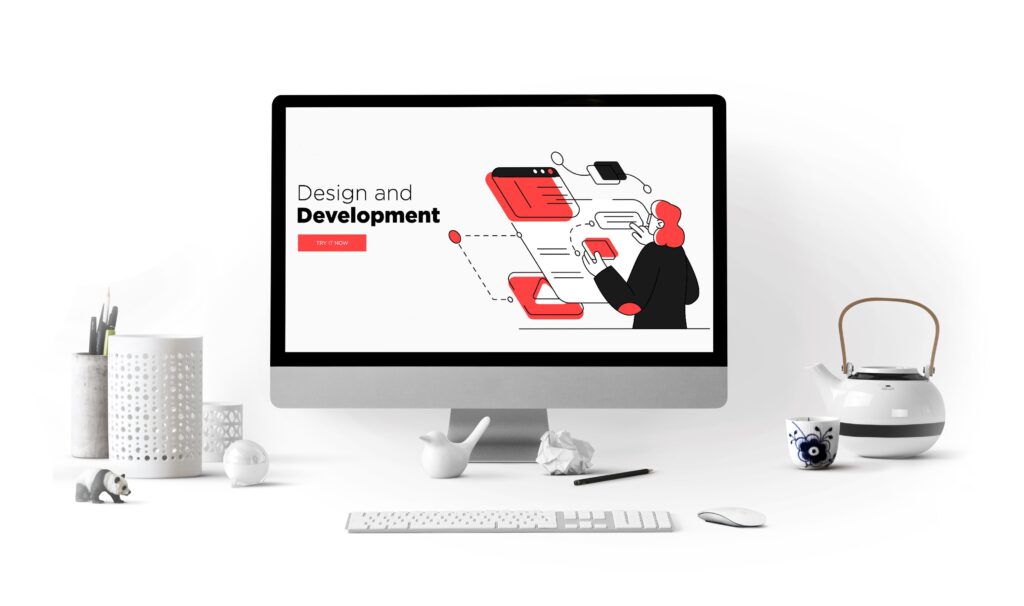 Computer monitor displaying ‘Design and Development’ surrounded by creative workspace items, representing Website Design and Development in the context of Creative Web Design Services.
