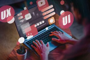 Mobile app development with a focus on user experience (UX) and user interface (UI) design, as indicated by the overlaid graphics on the laptop screen.